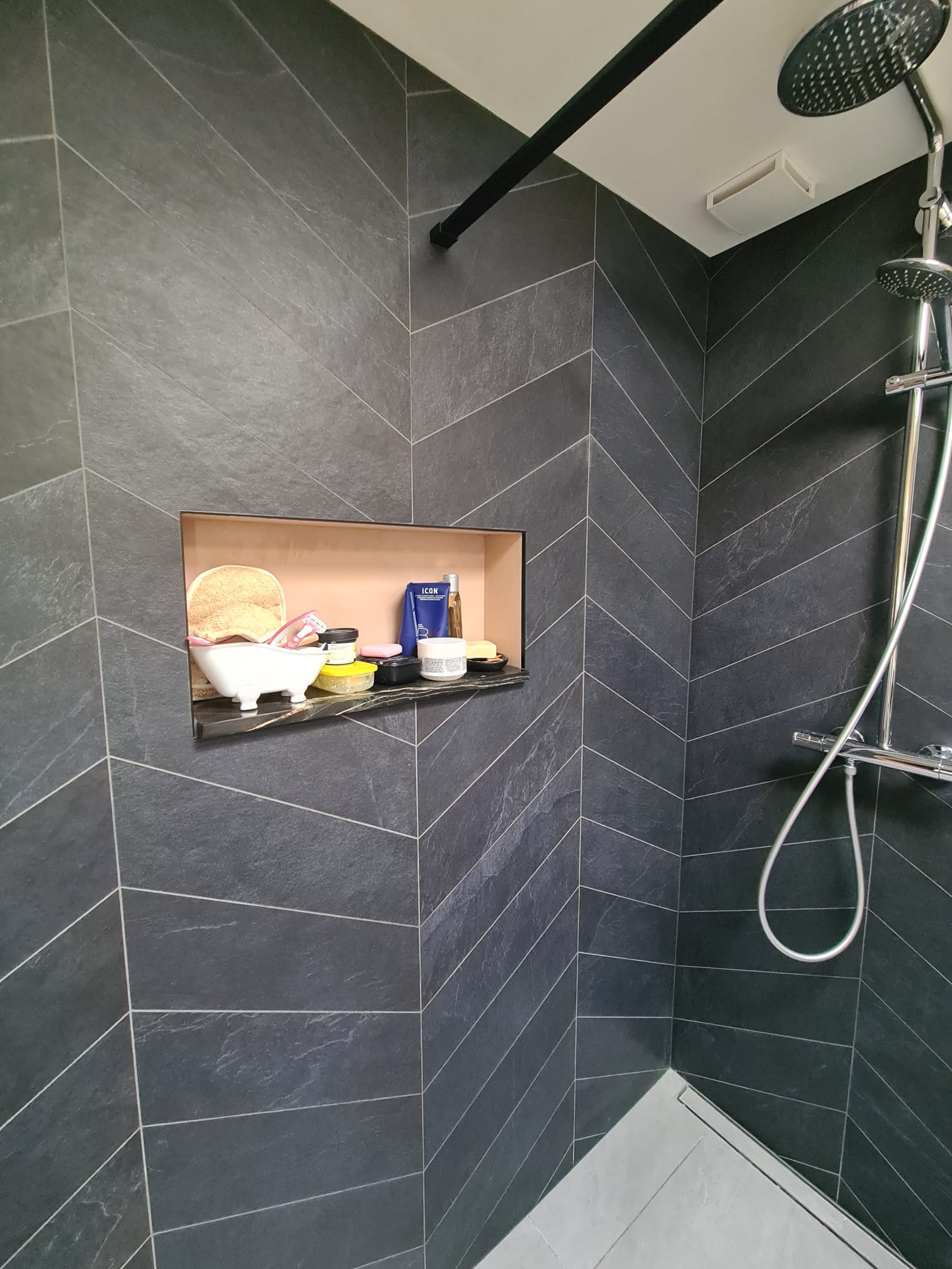 Inloopdouche met zwarte chevron tegels en nis